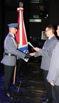 I Zastępca Śląskiego Komendanta Wojewódzkiego Policji insp. Roman Rabsztyn wręcza akt mianowania policjantowi z pocztu sztandarowego