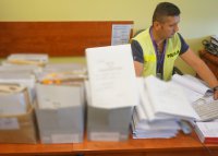 Policjant siedząc przy biurku sporządza dokumentację procesową