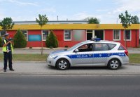 Policjant drogówki miernikiem dokonuje pomiaru prędkości dojeżdżającym pojazdom