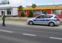 Policjant trzymając w ręku tarczę wydaje polecenie zatrzymania pojazdu