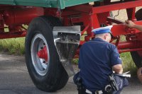 policjant ogląda uszkodzenia przyczepy ciągnika