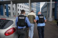 Policjanci doprowadzają zatrzymanego