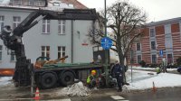 Dzielnicowy rozmawia z pracownikami wymieniającymi latarnie