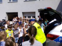 Dzieci i policjanci na parkingu wewnętrznym komendy