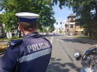 Policjant blokuje drogę na czas przemarszu procesji