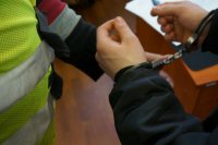 Policjant zakłada kajdanki włamywaczowi