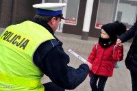 Na zdjęciu policjant wręcza dziecku odblask.