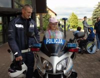 Na zdjęciu motocykl policyjny w trakcie pikniku a na nim siedząca dziewczynka.