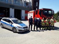 Na zdjęciu policjanci i strażacy na tle wozu strażackiego i radiowozu.