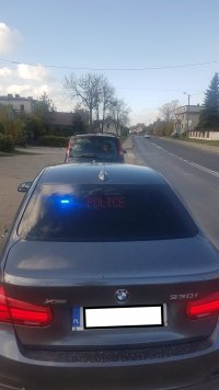 Na zdjęciu policjanci w nieoznakowanym  radiowozie przeprowadzają kontrolę drogową.