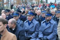 Na zdjęciu trzech policjantów w mundurach siedzą na ławce w trakcie mszy.