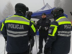 Na zdjęciu Komendant Wojewódzki Policji w Katowicach w trakcie uroczystej inauguracji ferii na stoku w Wiśle udziela wywiadu a na pierwszym planie dwóch policjantów patrolu na nartach.