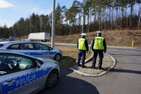 Na zdjęciu policjanci w mundurach w trakcie kontroli drogowej .