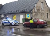 Na zdjęciu policjant stojący obok samochodu osobowego , którym poruszał się nietrzeźwy kierujący.