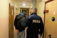 Na zdjęciu policjant w mundurze trzyma sprawcę kradzieży.