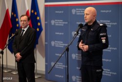 Na zdjęciu minister MSWIA Mariusz Kamiński oraz Komendant Główny Policji nadinsp. Andrzej Szymczyk w czasie konferencji prasowej stoją na tle flag państwowych.