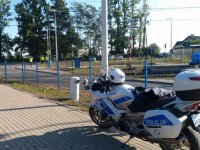 Na zdjęciu policyjny motocykl stojący obok przejazdu kolejowego w Rusinowicach.