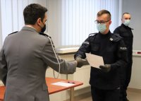Na zdjęciu Komendant Powiatowy w Lublińcu wręcza legitymacje nowo przyjętemu policjantowi.