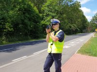 Na zdjęciu policjant mierzący prędkość pojazdów na drodze.