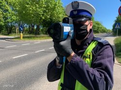 Na zdjęciu policjant z miernikiem prędkośći prowadzący działania na drodze.