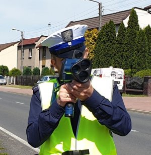 Na zdjęciu policjant wydziału ruchu drogowego, mierzący prędkość.