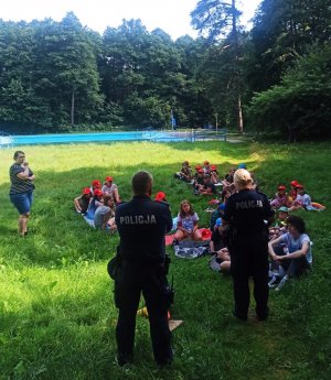 Zdjęcia przedstawiają policjantów omawiających z dziećmi temat bezpieczeństwa nad wodami.