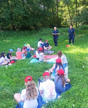 Zdjęcia przedstawiają policjantów omawiających z dziećmi temat bezpieczeństwa nad wodami.