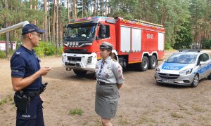 Na zdjęciu policjant w trakcie kontroli obozu harcerskiego w Kokotku rozmawia z kobietą w mundurze harcerskim.