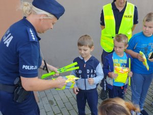 Na zdjęciu policjantka rozdaje odblaski uczniom szkoły w Sadowie.