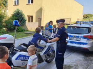 Na zdjęciu uczniowie oglądają policyjny motocykl i radiowóz.