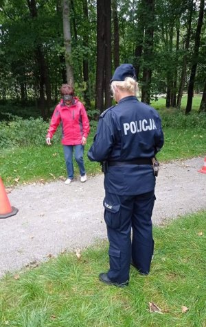 Na zdjęciu policjantka w mundurze i osoba pokonująca tor przeszkód.