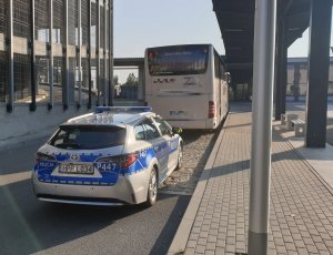 Na zdjęciu widoczny radiowóz policyjny w trakcie kontroli autobusu.