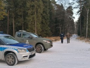 Na zdjęciu policyjny radiowóz i samochód Straży Leśnej.