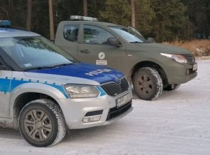 Na zdjeciu poliyjny radiowóz i samochód Straży Leśnej w czasie działań Choinka 2021.