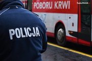 Na zdjęciu policjat stojący na tle autobusu, w którym pobierana jest krew.