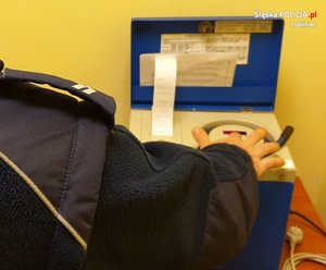 Na zdjeciu policjant wykonujący badanie stanu trzeźwości za pomocą alkomatu.