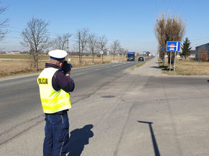 Na zdjęciu policjant na drodze mierzący prędkość.