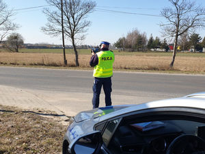 Na zdjęciu policjant na drodze mierzący prędkość.