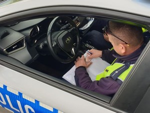 Na zdjęciu policjant wypisuje mandat karny.