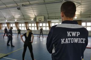 Na zdjęciu wnętrze sali sportowej z torem przeszkód i stojący tyłem instruktor w koszulce KWP Katowice.