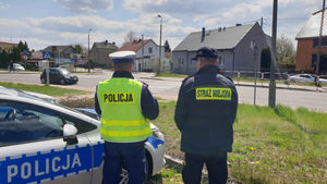 Na zdjęciu policjant ze strażnikiem miejskim obserwuje przejście dla pieszych.