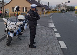 Na zdjęciu policjant drogówki w trakcie pełnienia służby na drodze. Policjant mierzy prędkość pojazdów .