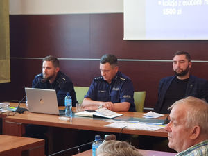 Na zdjęciu I Zastępca Komendanta Powiatowego Policji w Lublińcu, policjant z Wydziału Ruchu Drogowego siedzący przy stole w trakcie debaty w Woźnikach.