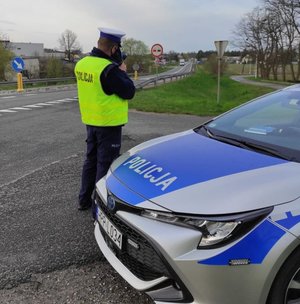 Na zdjęciu policjant w trakcie zatrzymywania pojazdu na drodze.