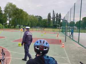 Na zdjęciu policjant obserwuje przebieg egzaminu na kartę rowerową.