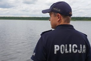 Na zdjęciu policjant na tle zbiornika wodnego.