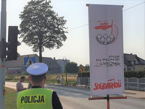 Na zdjęciu policjant i flaga z logiem wyścigu kolarskiego.