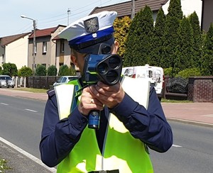 Na zdjęciu policjant w trakcie pomiaru prędkości na drodze.