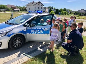 Na zdjęciu policjanci i przedszkolaki podczas prelekcji, w trakcie oglądania policyjnego samochodu.