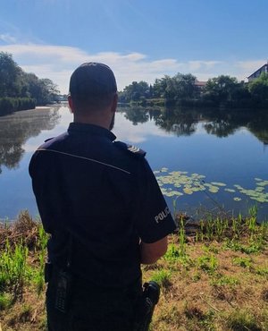 Na zdjęciu policjant kontrolujący zbiornik wodny.